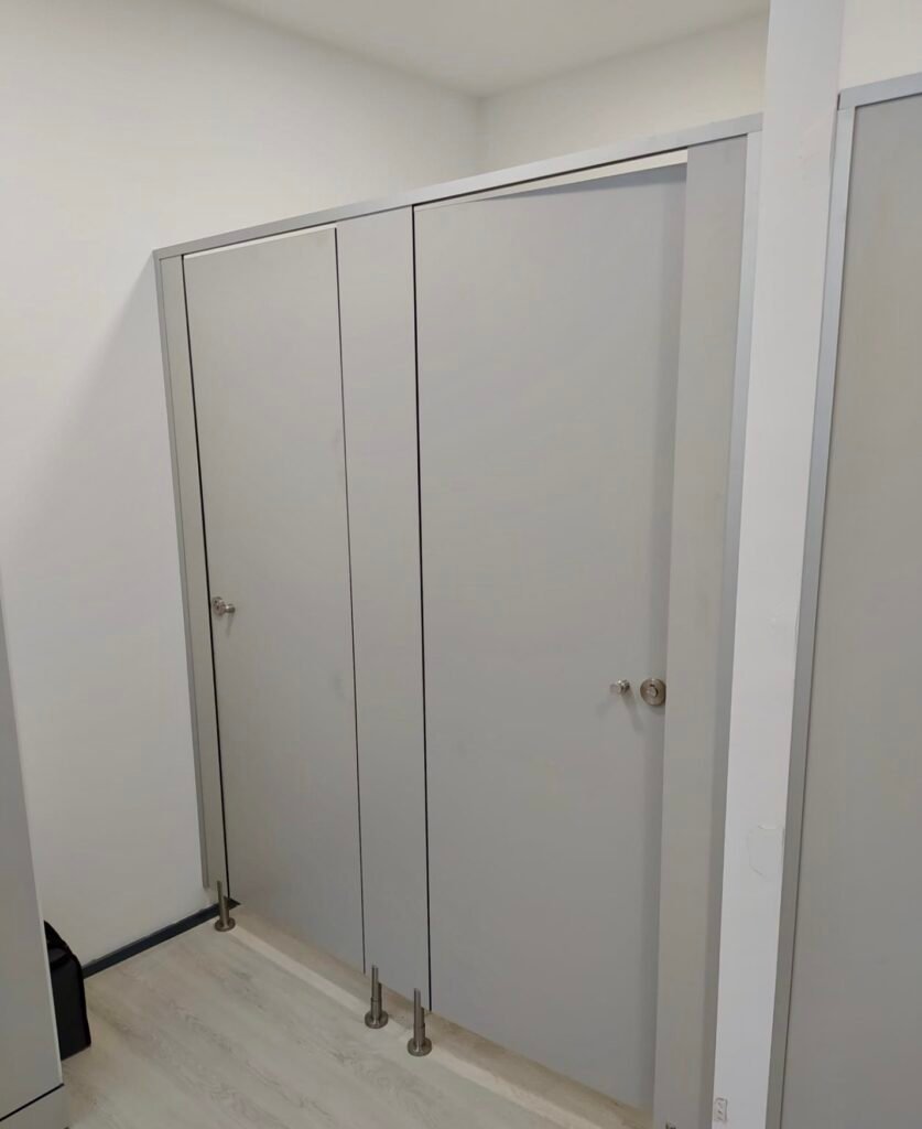 Vue d'ensemble d'un espace vestiaires avec cabines douches, casiers et bancs en stratifié compact