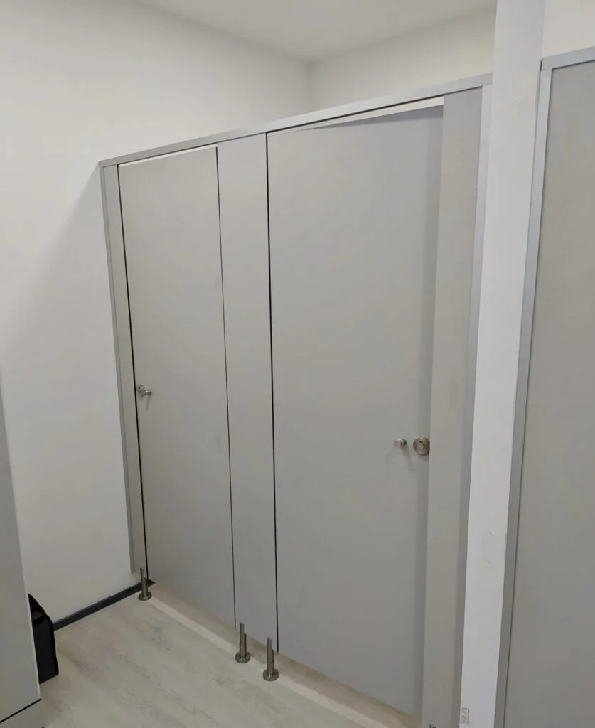 Vue d'ensemble d'un espace vestiaires avec cabines douches, casiers et bancs en stratifié compact