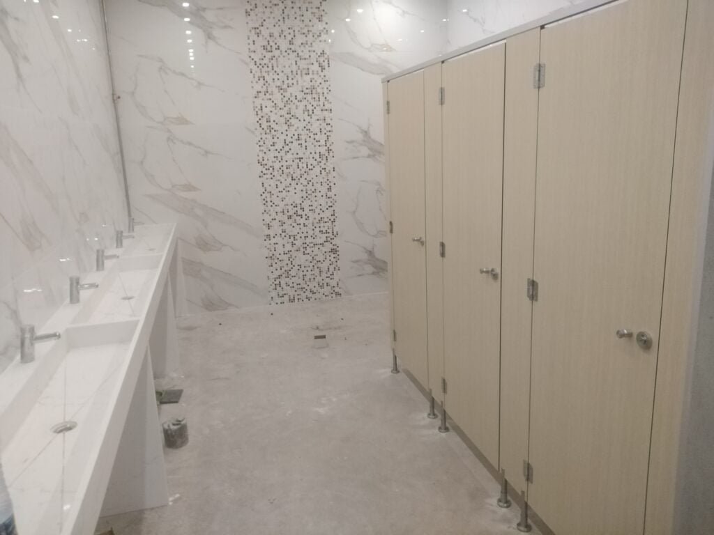 Aménagement des vestiaires humides pour une salle de sport avec des cabines stratifiées.