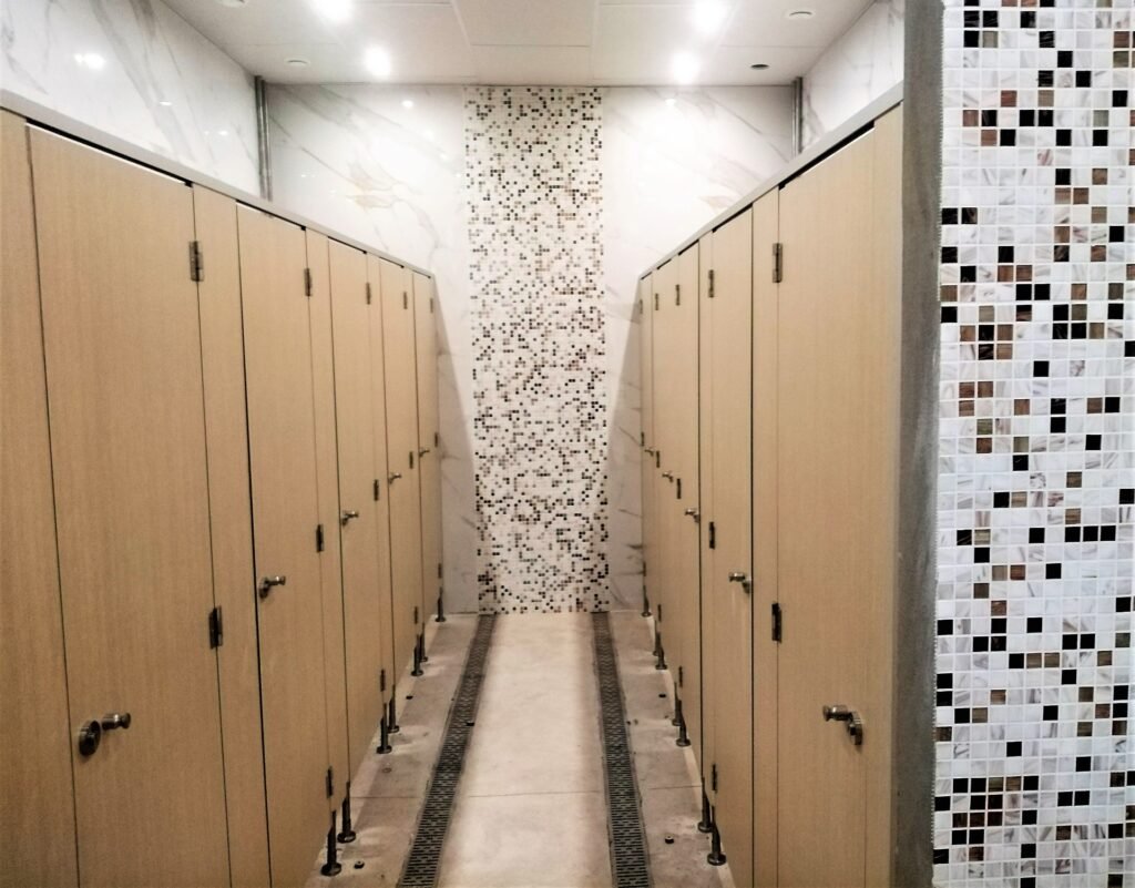 Rangée de casiers stratifiés en bois clair dans une salle d'eau moderne avec mosaïque murale, symbolisant l'entretien des cabines sanitaires