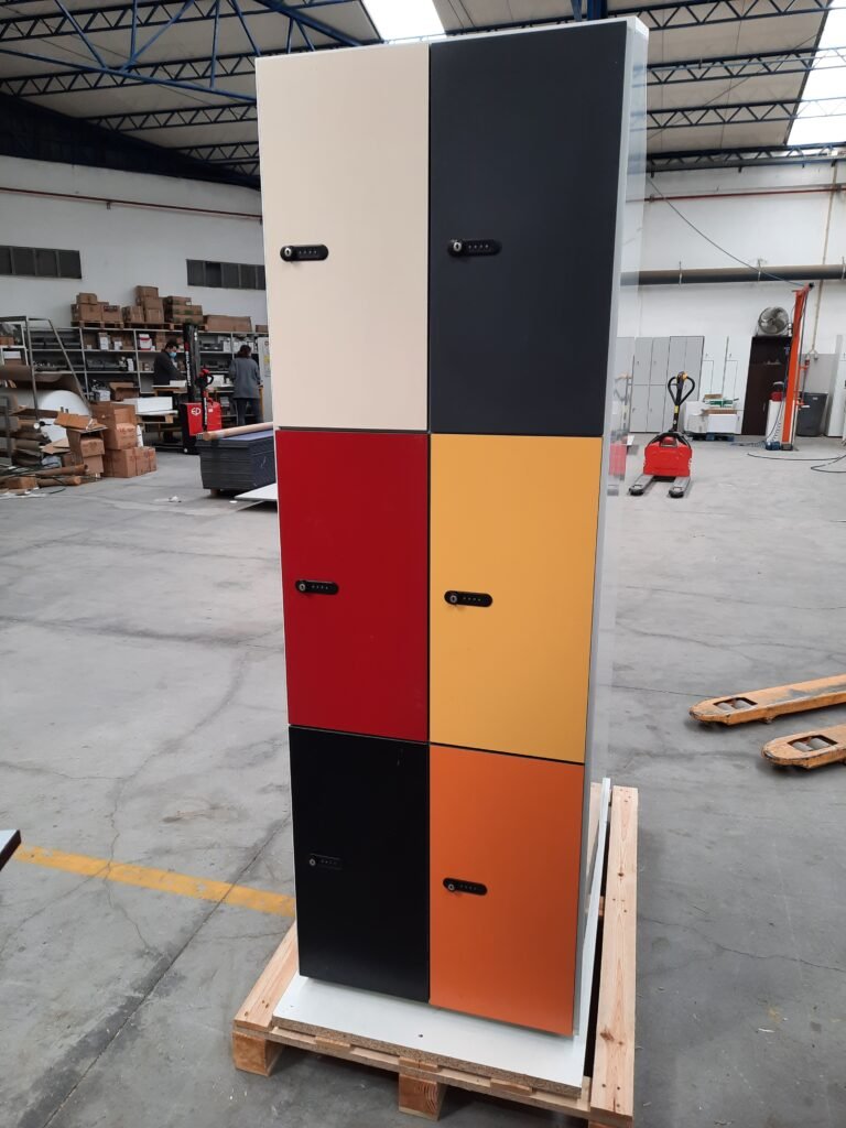 Colonne de 6 casiers vestiaires en stratifié compact HPL avec portes de couleurs vives contrastées (blanc, noir, rouge, orange foncé, orange clair), équipés de serrures à code mécanique à touches, sur palette en atelier