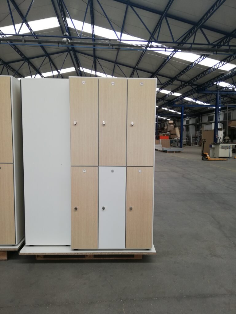 Batterie de casiers vestiaires en stratifié compact HPL, portes bicolores chêne clair et gris, configuration 2 cases par colonne, photographiée en atelier avant expédition