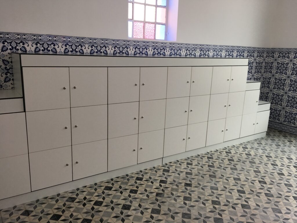 Colonnes de casiers penderie pleine hauteur en stratifié compact HPL coloris gris anthracite mat, configuration 1 case par colonne avec compartiment inférieur, équipés de lecteurs RFID noirs, sur palettes en atelier avant livraison